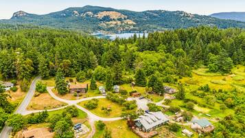 An aerial view of a residential area with houses, roads, and a lake surrounded by forested hills.