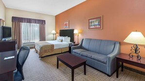 A hotel room with a bed, a sofa, a desk, and a TV. - Wingate by Wyndham West Monroe (West Monroe)