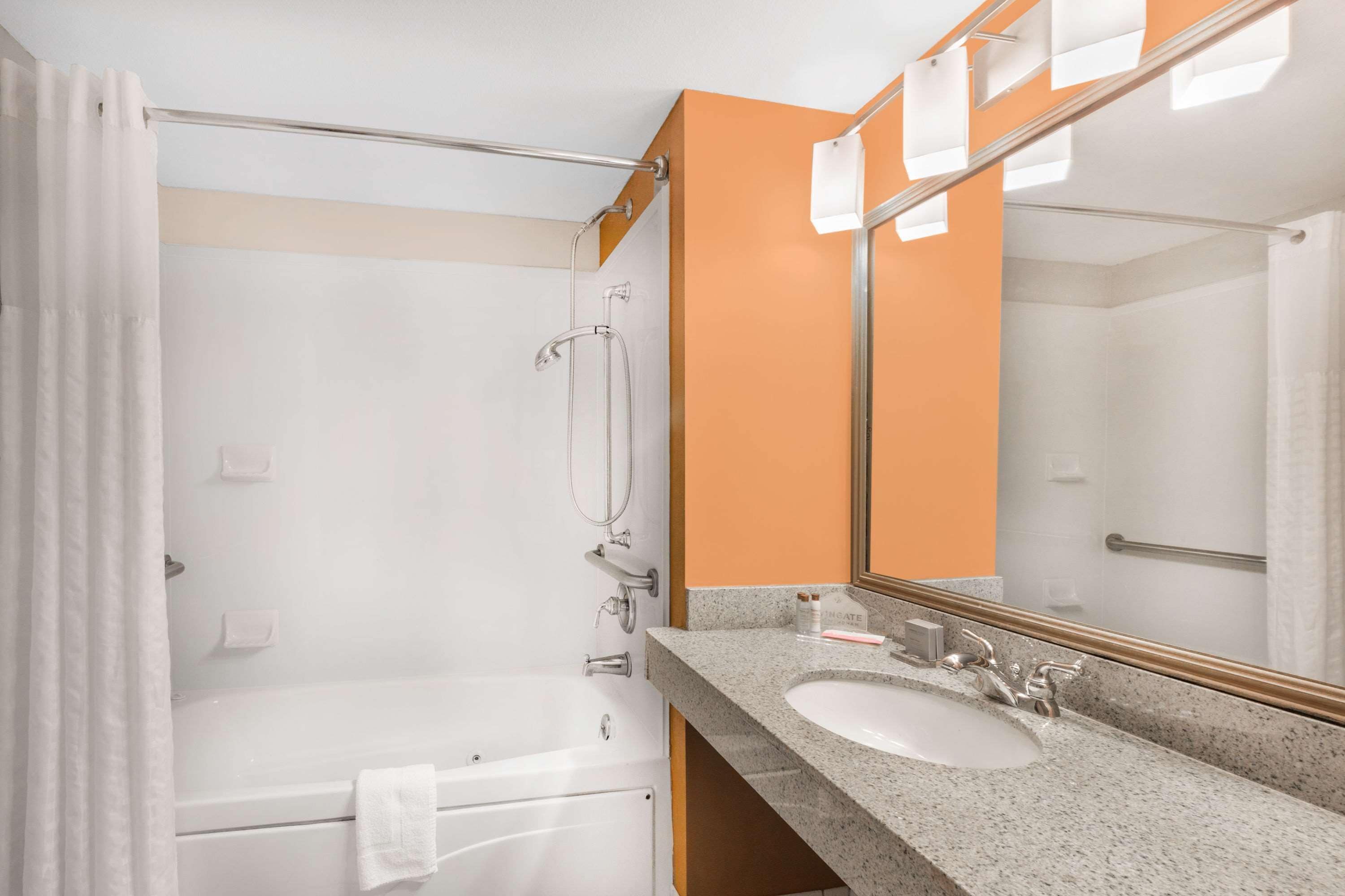 A bathroom with a bathtub, a sink, and a large mirror.