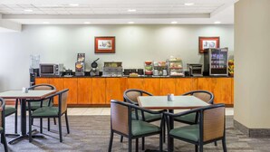 A hotel dining area with a counter, microwave, coffee machine, and seating. - Wingate by Wyndham West Monroe (West Monroe)