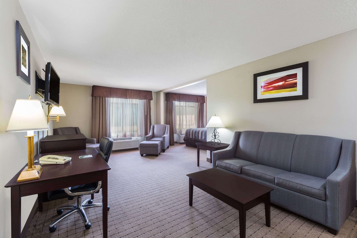 Ein Hotelzimmer mit Schreibtisch, zwei Stühlen, einer Couch und einem Fernseher.
