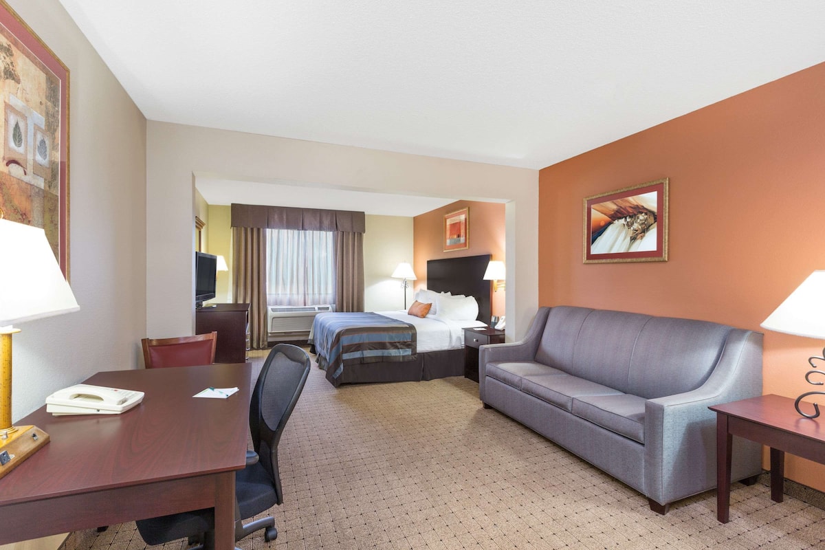 Ein Hotelzimmer mit Bett, Sofa, Schreibtisch und Fernseher.