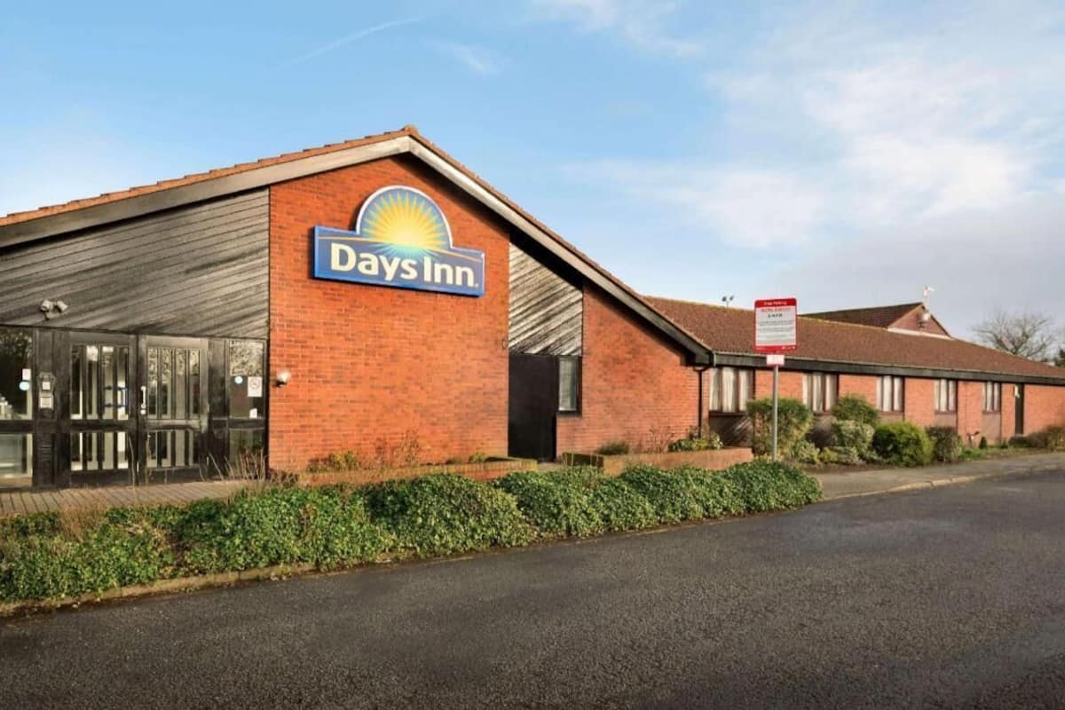 A Days Inn building with a brick facade, a large glass entrance, and a clear sky.