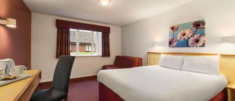 A hotel room with a large bed, a desk with a chair, a window with curtains, and a painting on the wall.