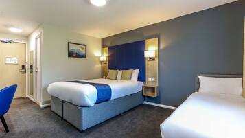 A hotel room with a large bed, a chair, a desk, and a wall-mounted shelf.