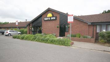 Un hotel Days Inn con fachada de ladrillo, una entrada visible y un estacionamiento con automóviles.