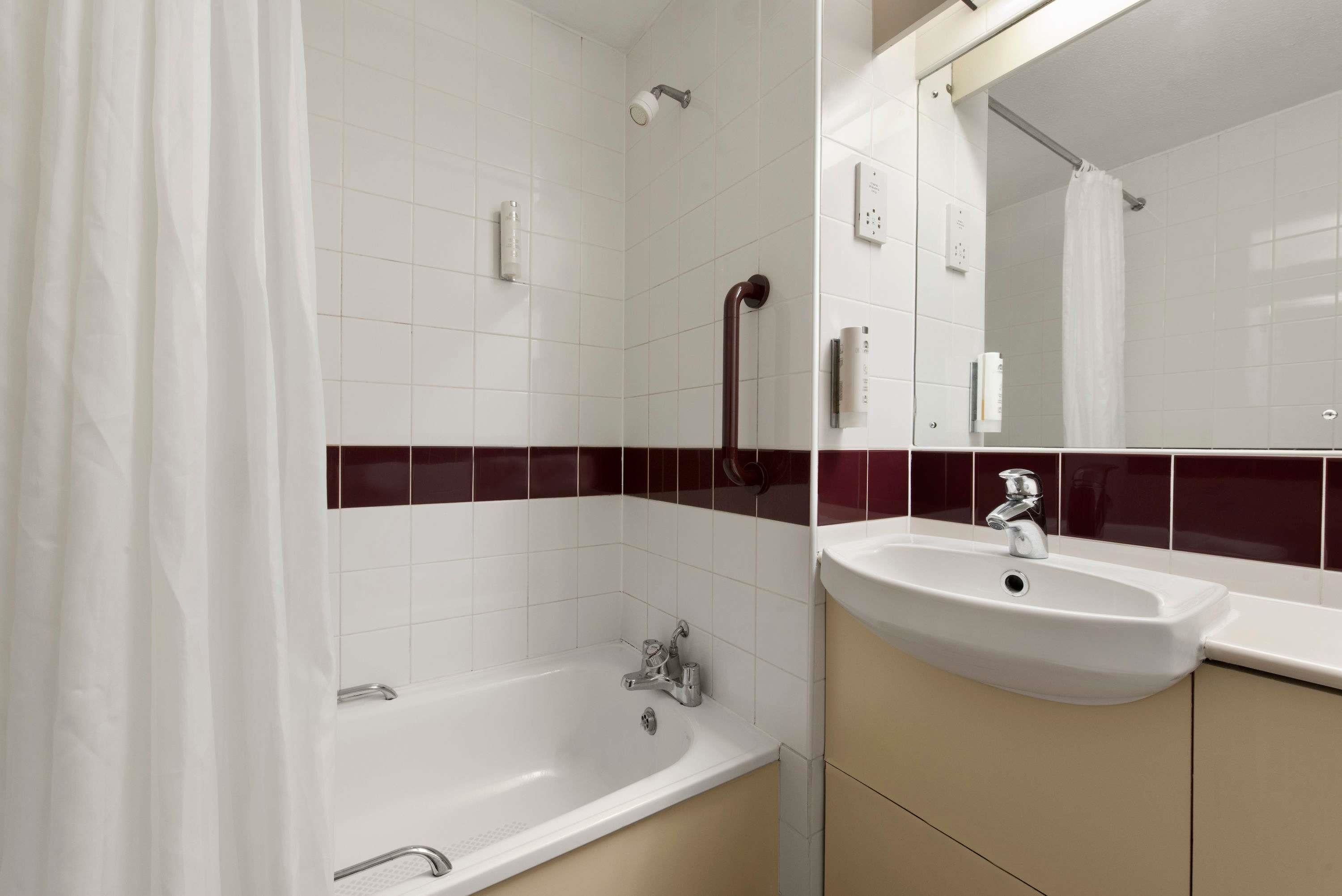 A bathroom with a bathtub, a sink, and a mirror.