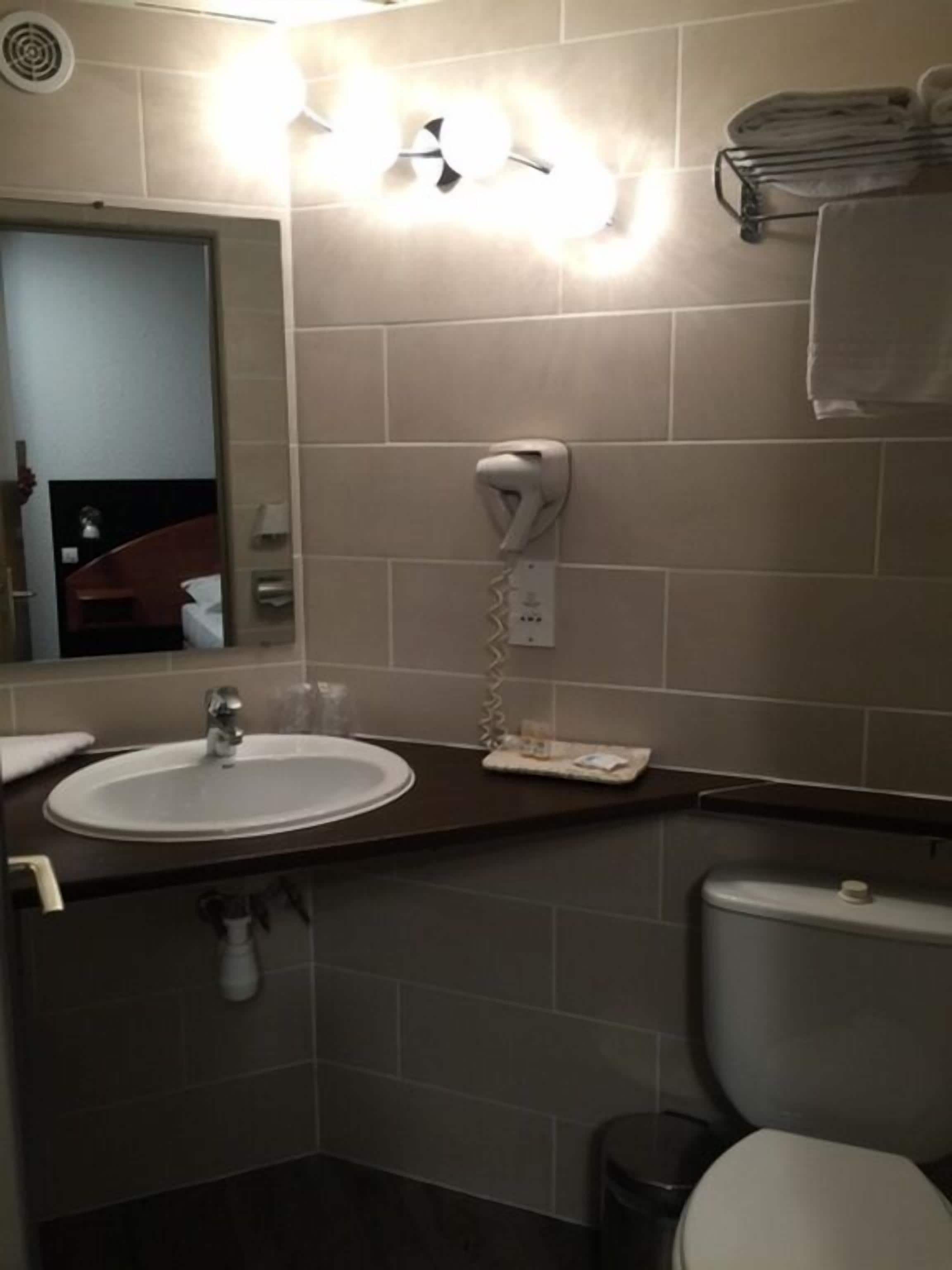 A bathroom with a sink, toilet, and a towel rack.