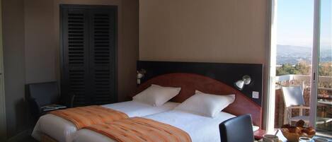 A hotel room with a bed, a desk with breakfast, and a view of the city.