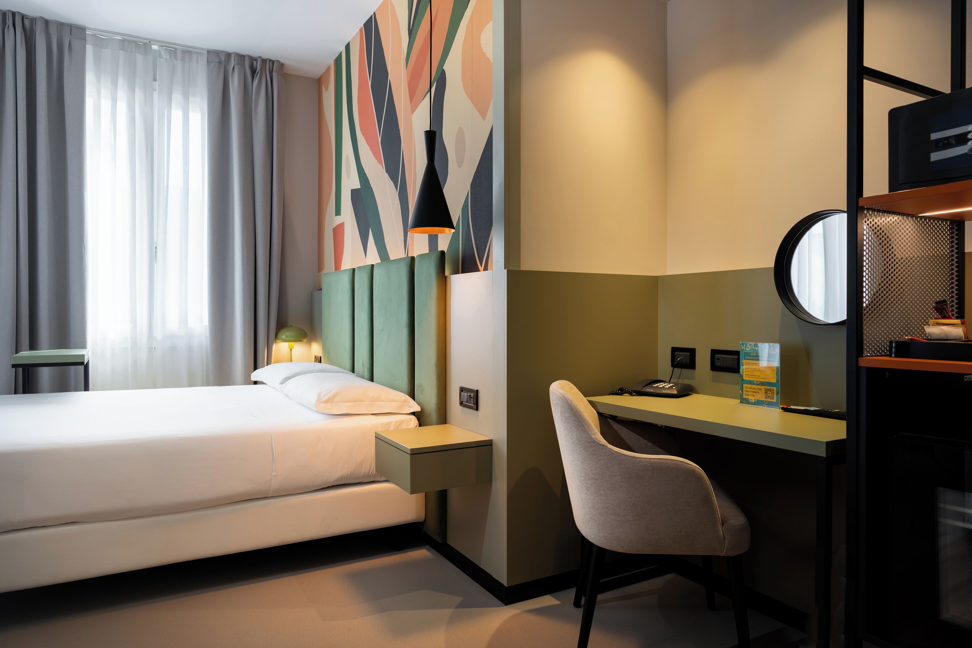 Habitación de hotel con cama, escritorio, silla y un cuadro abstracto grande en la pared.
