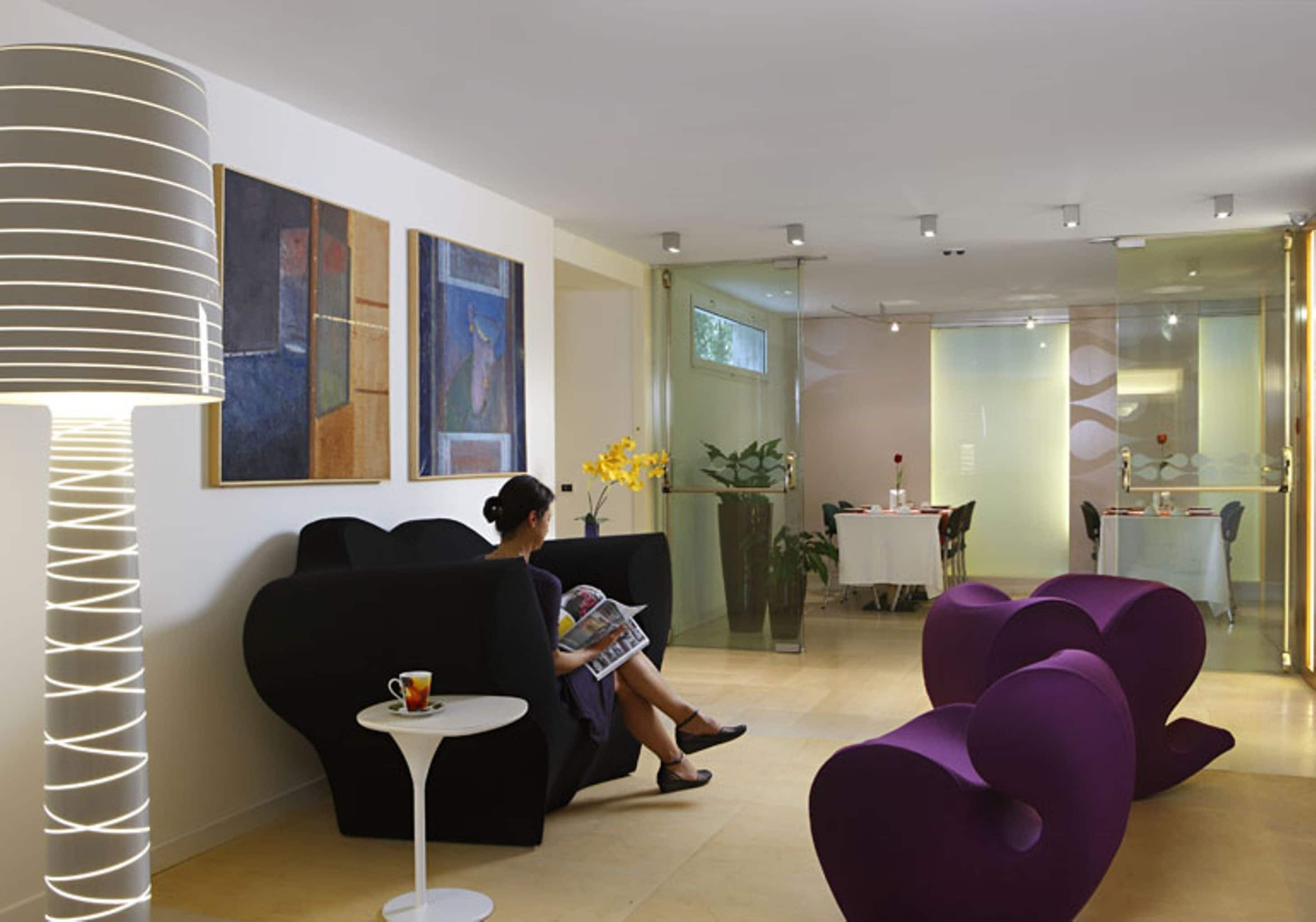 A modern lobby with black sofas, a white table, and a glass partition.