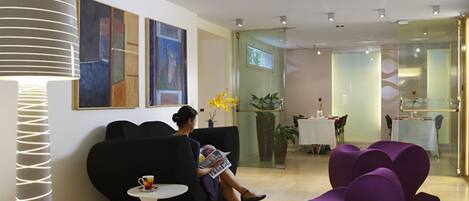 A modern lobby with black sofas, a white table, and a glass partition.