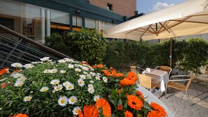 An outdoor seating area with tables and chairs, surrounded by a variety of flowers. - Elite Hotel & Spa (Mestre)