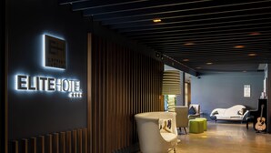 A modern hotel lobby with a reception desk, seating area, and a piano. - Elite Hotel & Spa (Mestre)