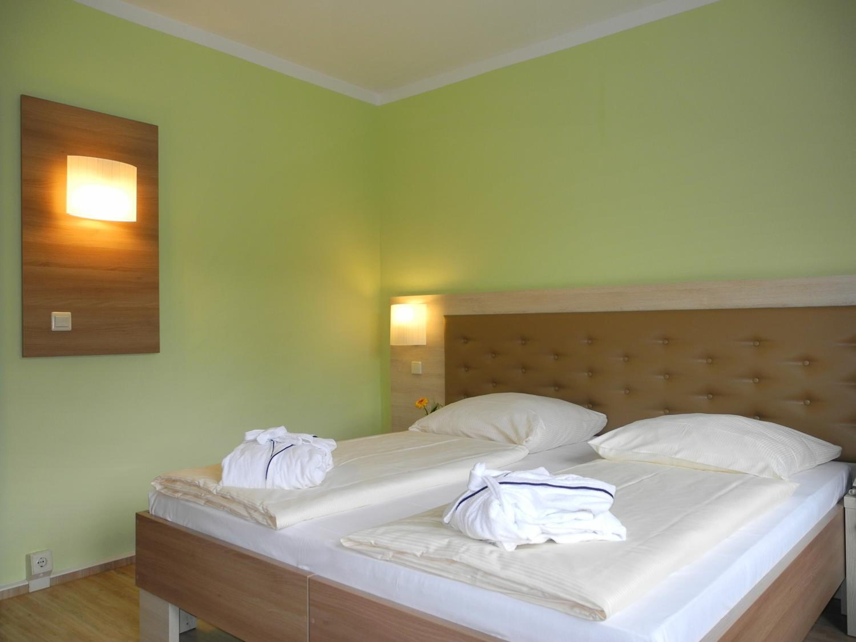 A double bed with a wooden headboard and two bedside lamps.