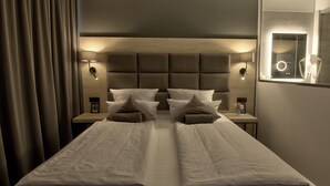 Una cama doble con dos mesitas de noche, cada una con una lámpara, en una habitación de hotel moderna.