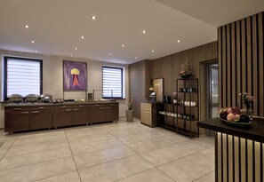 A modern kitchen with a long counter, built-in appliances, and a decorative wall piece. - Waldhotel Wandlitz (Wandlitz)