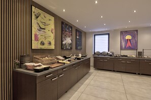 Una cocina moderna con una isla central, paneles de madera y obras de arte en las paredes.
