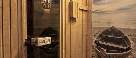 A sauna room with a wooden door, a sign indicating 'SAUNA REGELI,' and a view of a boat on the beach through the window.