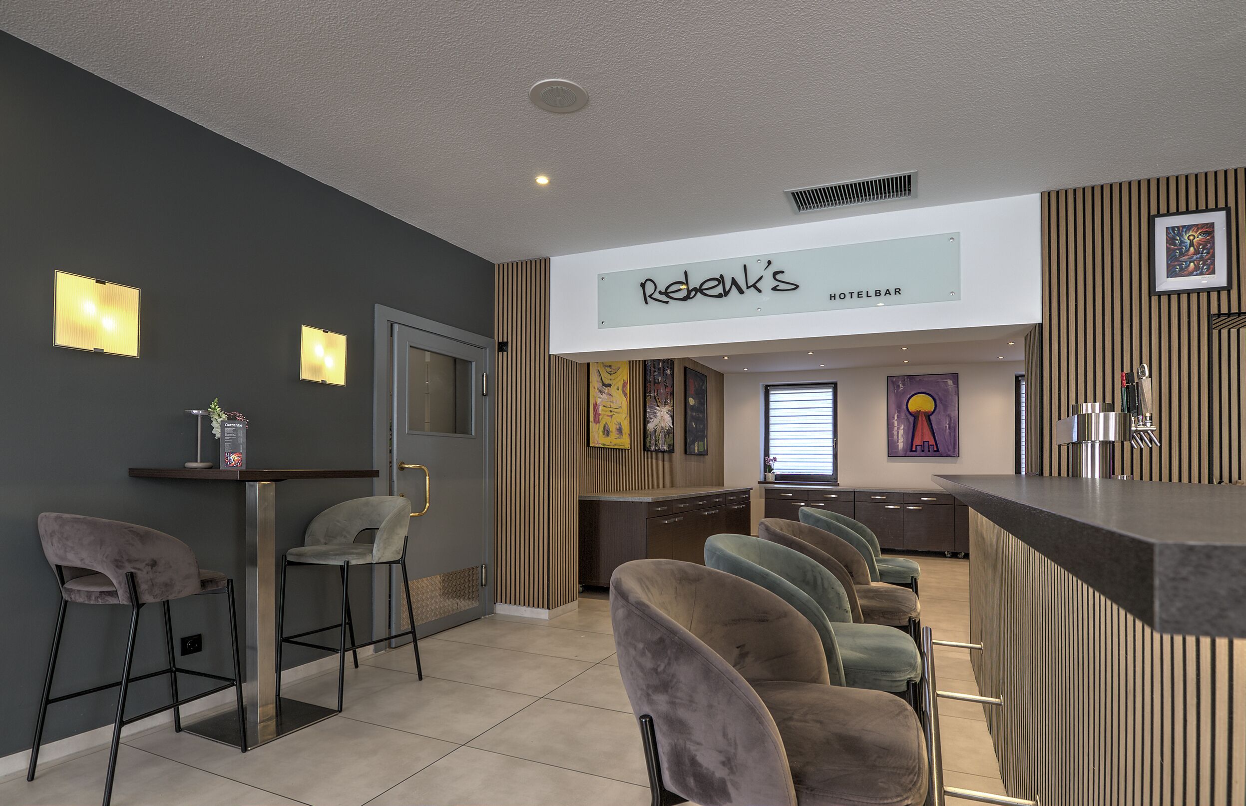 Um bar moderno de hotel com balcão, banquetas acolchoadas e um letreiro indicando 'Rebentz's HOTEL BAR'.
