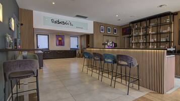 A hotel bar with a modern design, featuring a bar counter, multiple seating options, and a visible sign for 'Rebek's Hotel Bar'.