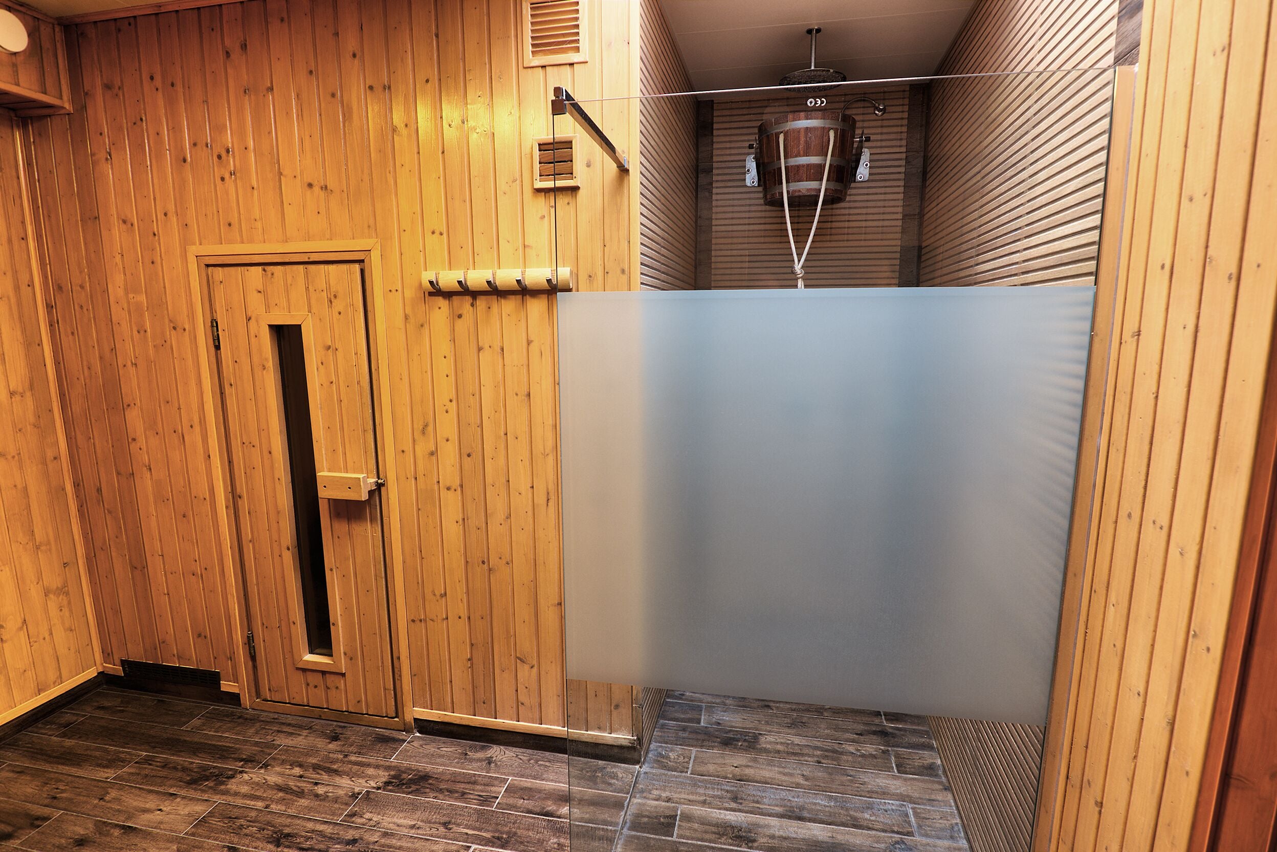 A wooden-paneled room with a door, a small window, and a wooden ceiling.