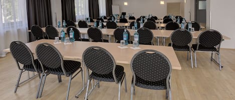 A conference room with multiple tables and chairs, water bottles, and a whiteboard.