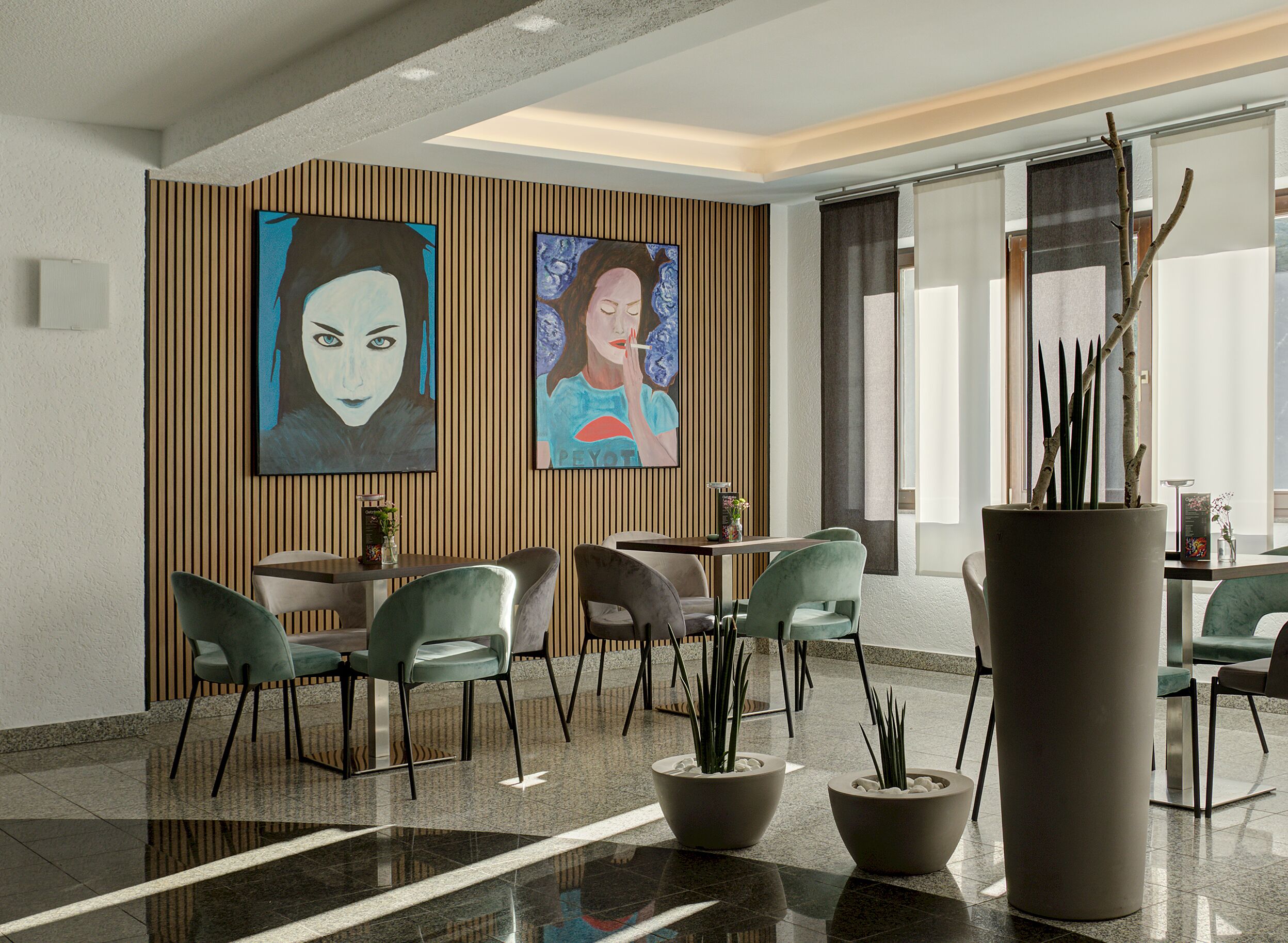 Un vestíbulo moderno con piso pulido, zona de estar con sillones, mostrador de recepción y dos grandes cuadros colgados en la pared.