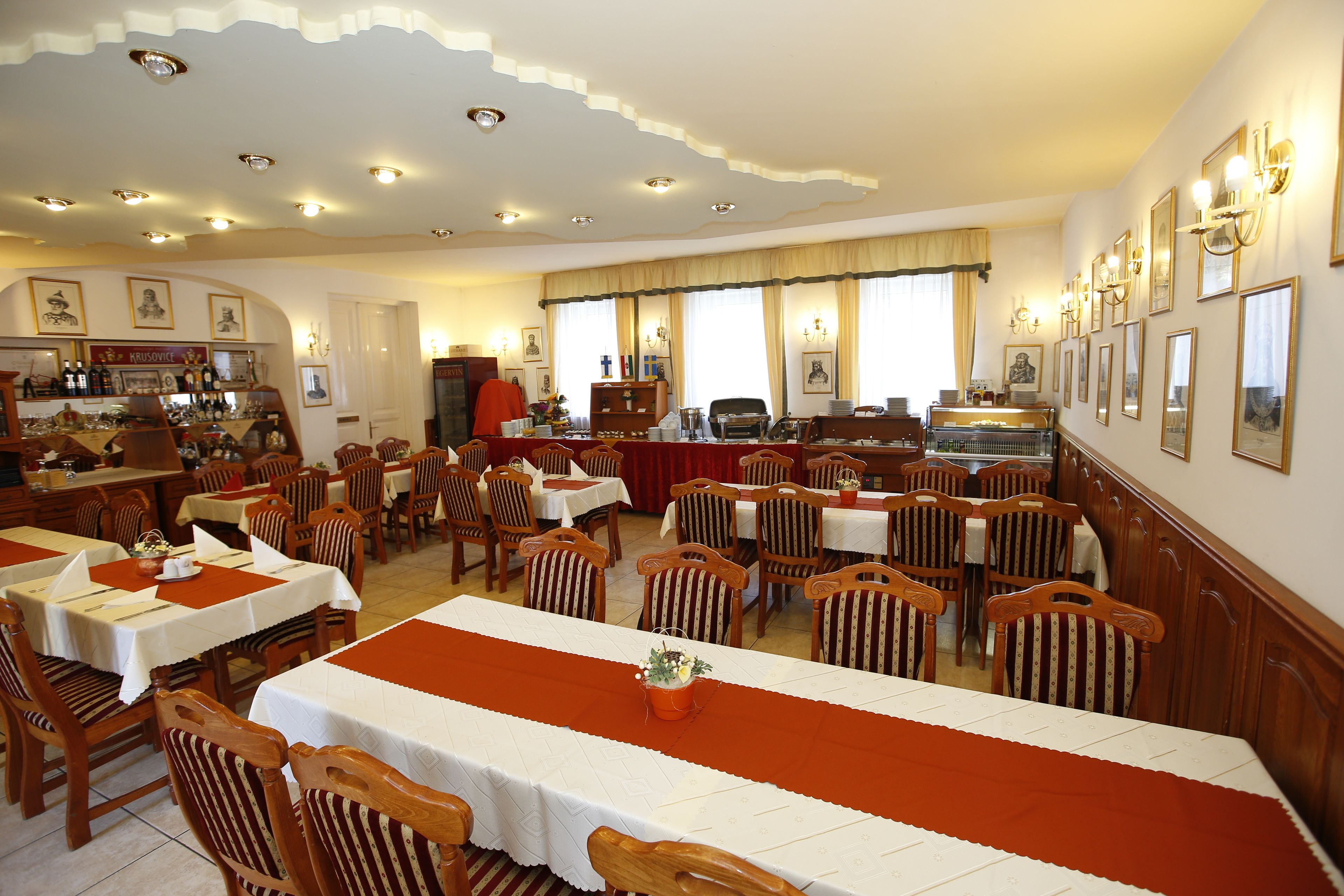 Un restaurante con varias mesas y sillas, una zona de bar y diversas fotografías enmarcadas en las paredes.