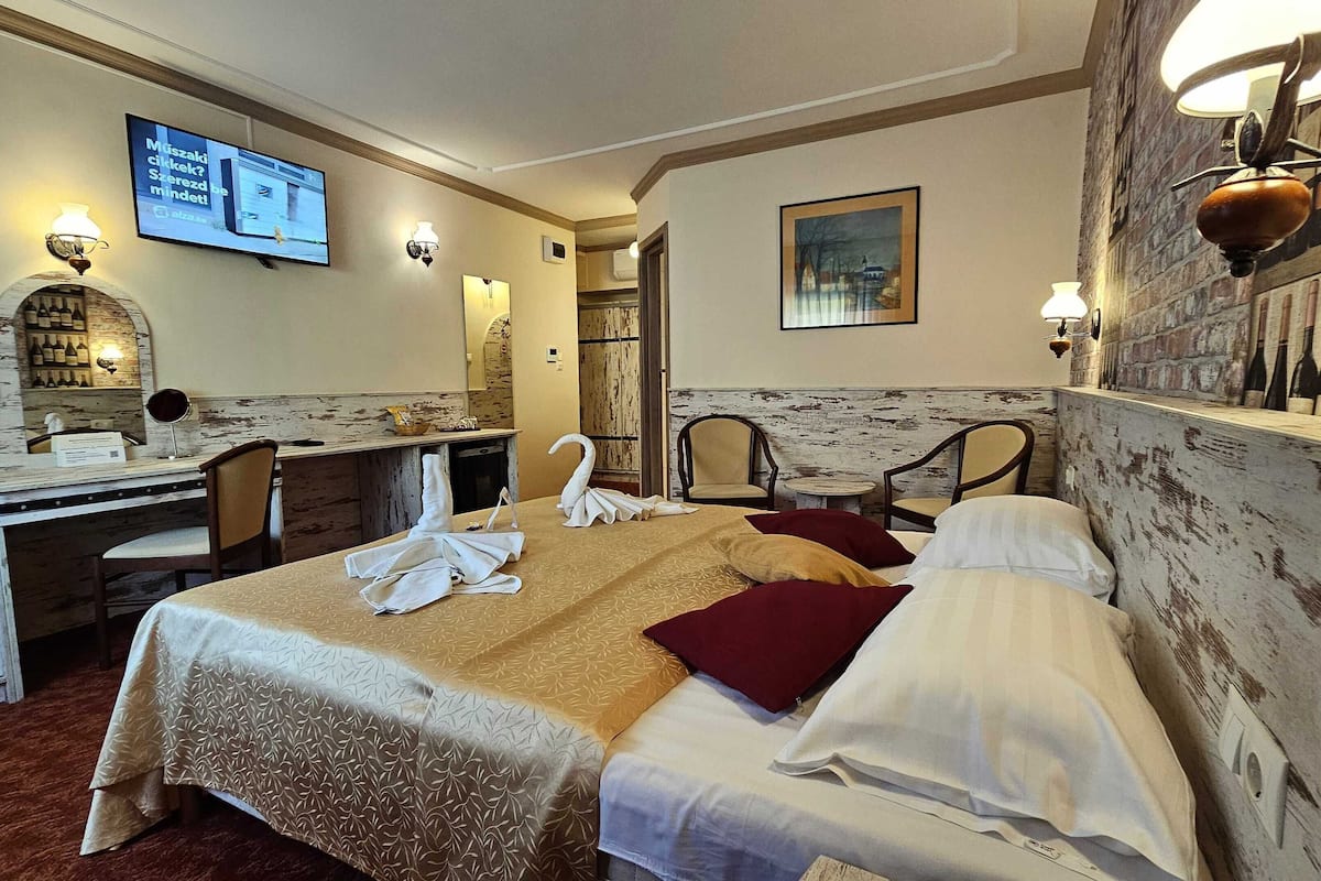 Ein Hotelzimmer mit zwei Betten, einem Schreibtisch, einem Fernseher und einer Wand mit Weinflaschen.