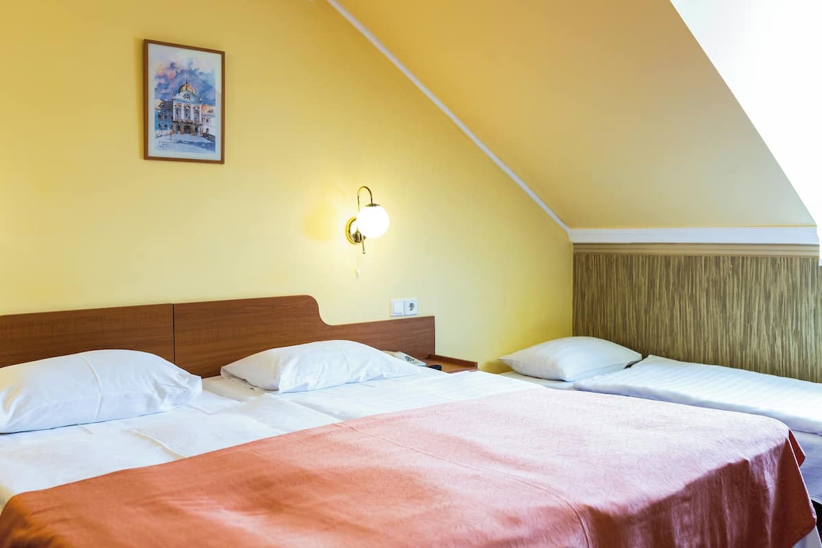 Ein Hotelzimmer mit zwei Betten, einem Holzkopfstück, einem Bild an der Wand und einer Wandleuchte.
