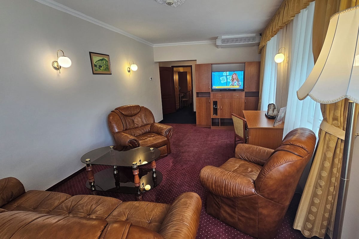 Ein Wohnzimmer mit Ledersofas, einem Glastisch und einem Fernseher.