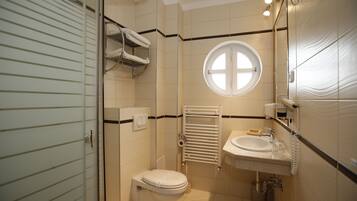 Et badeværelse med toilet, vask, håndklædetørrestativ og et vindue.