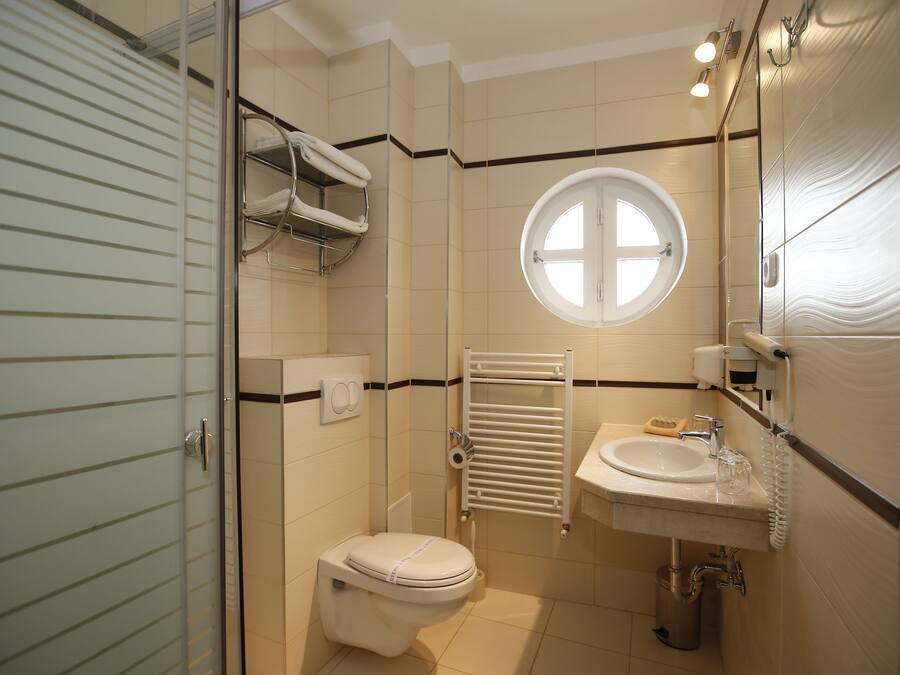 Un baño con inodoro, lavamanos, perchero para toallas y ventana.
