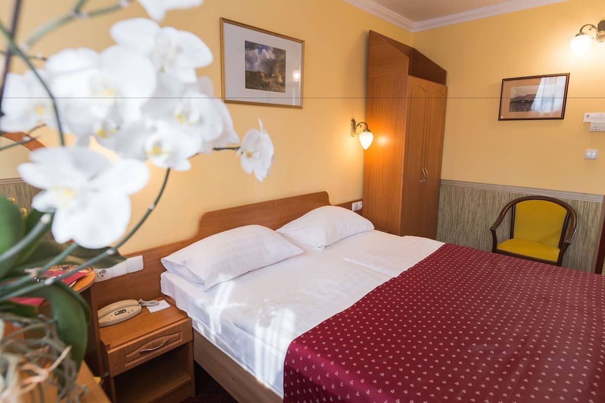 Ein Hotelzimmer mit Bett, Nachttisch mit Telefon, Stuhl und Wandleuchte.