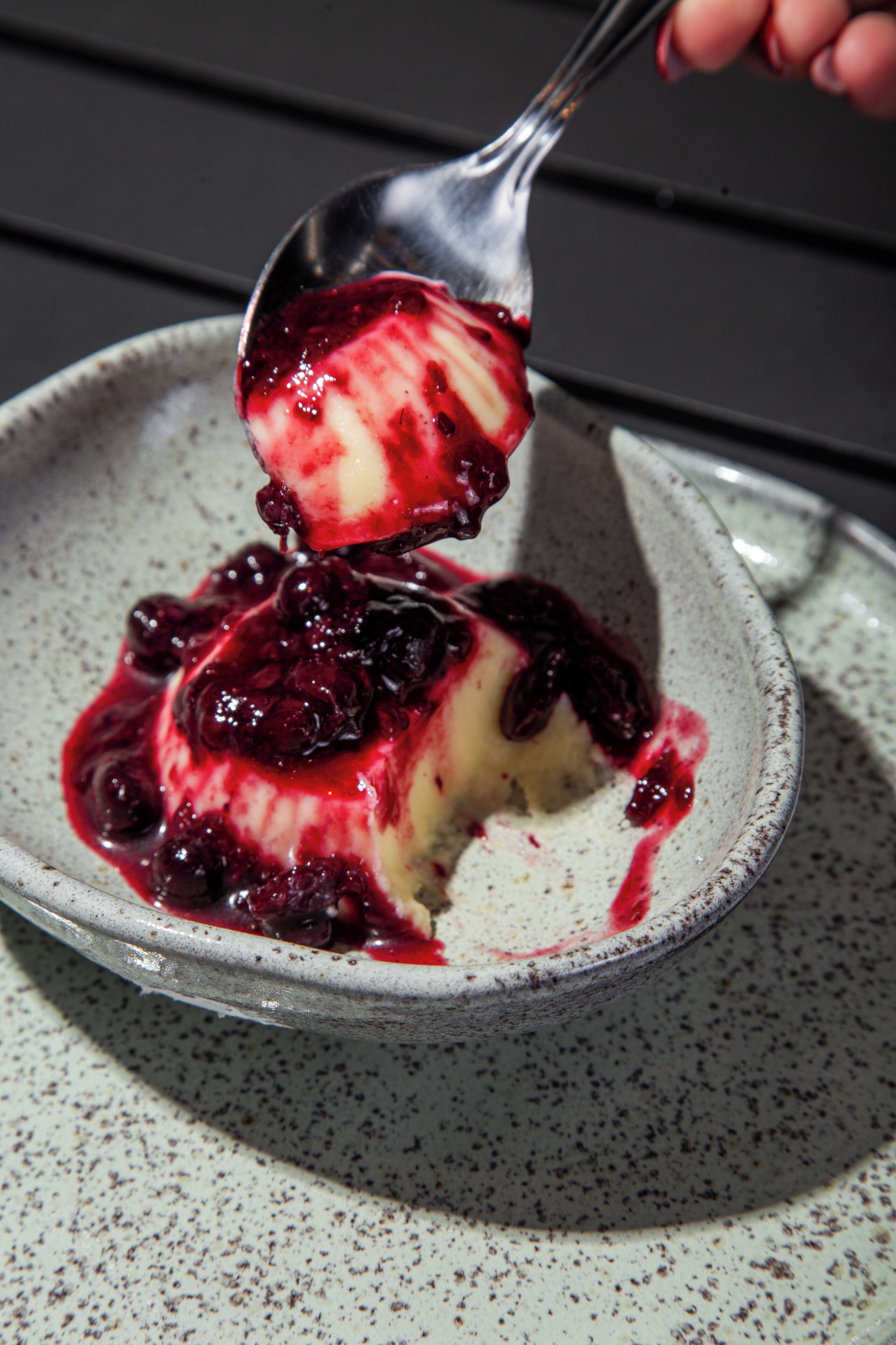 A dessert with a scoop of ice cream and berries on a ceramic plate.
