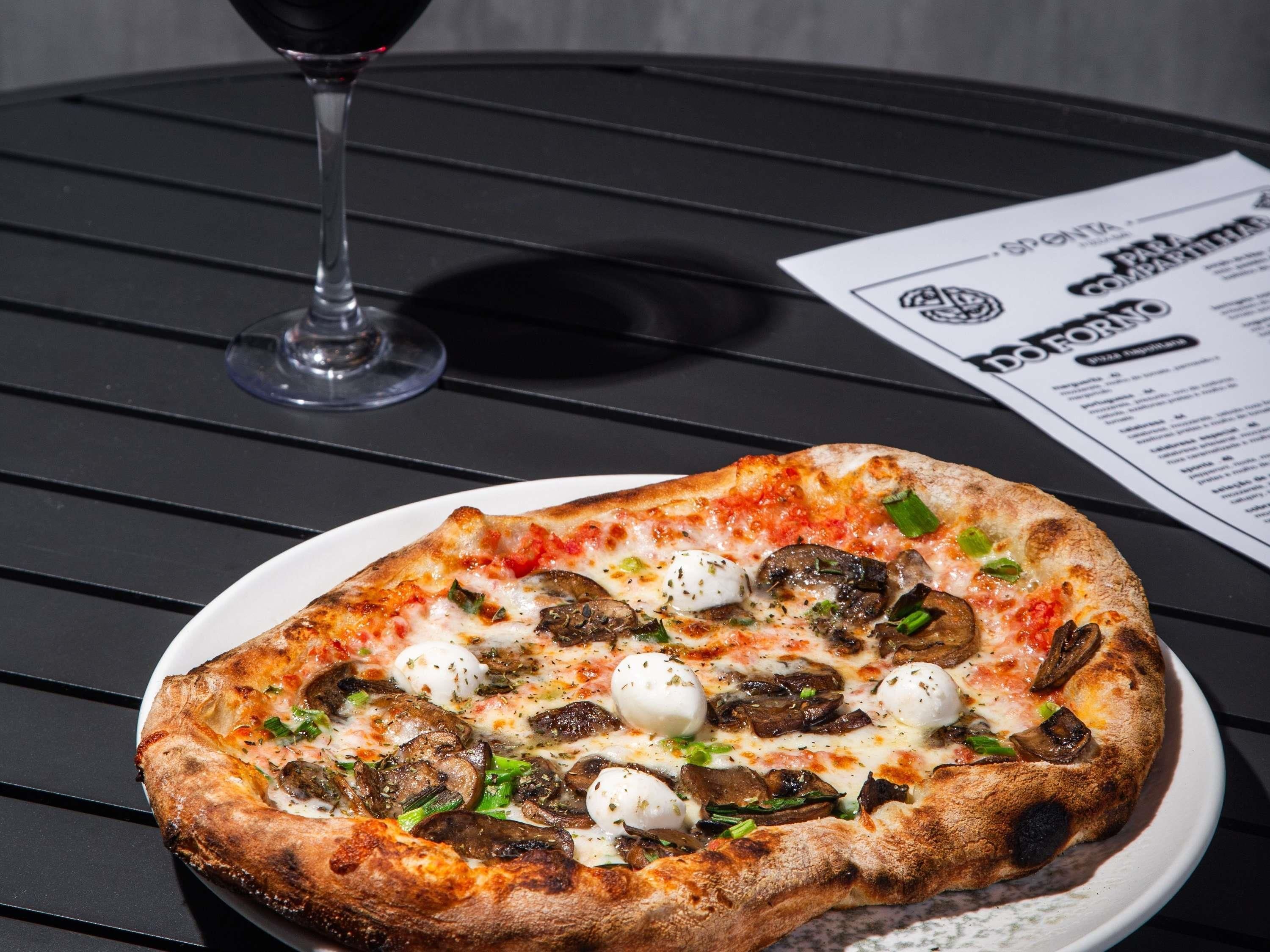 A pizza on a white plate with a menu beside it.