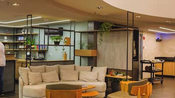 Un interior moderno con techo curvo, una zona de estar con sofás y sillones, una cocina con encimera y electrodomésticos, y una cámara de seguridad.