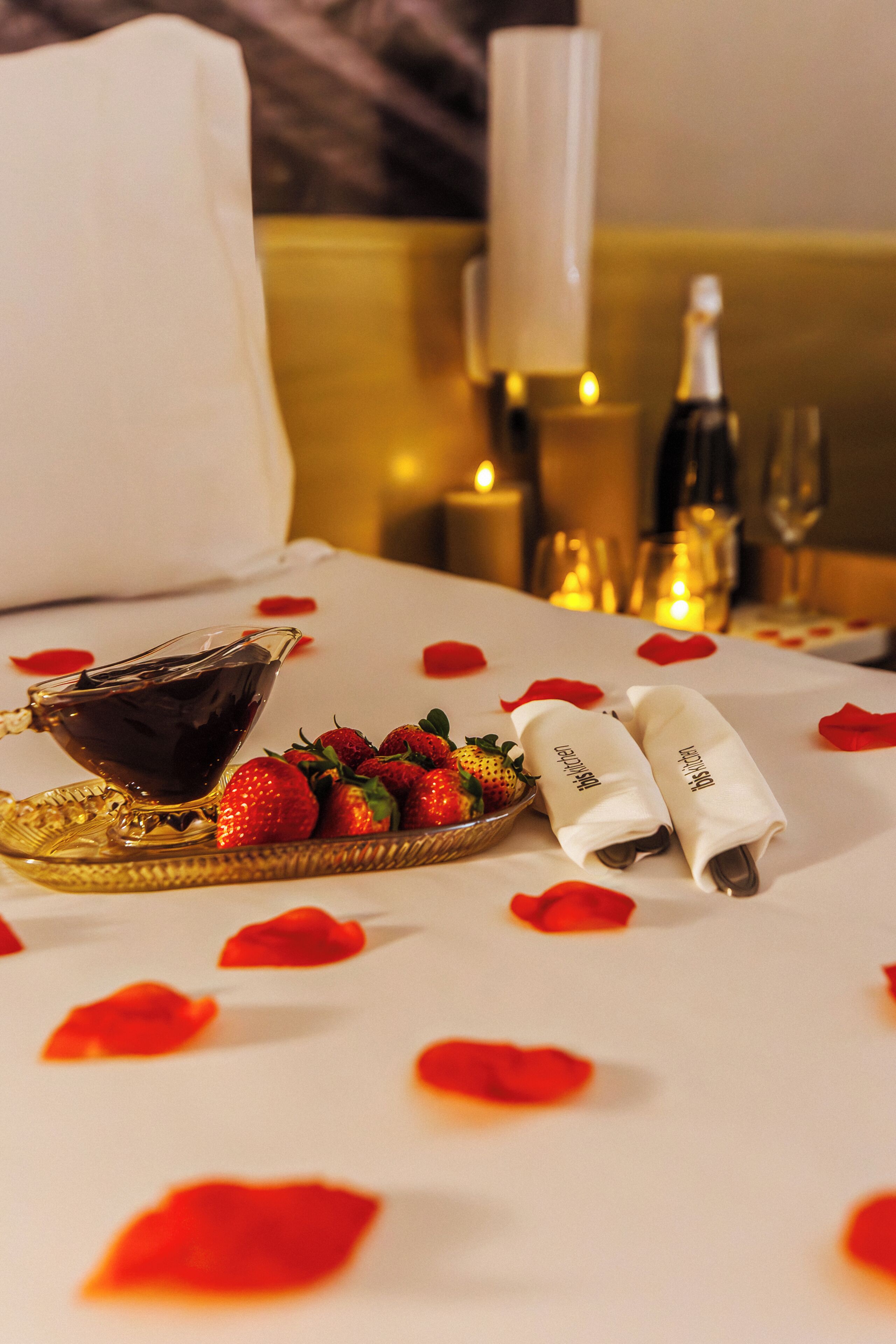A neatly arranged table with a plate of strawberries, a bowl of chocolate sauce, and two napkins with a logo.