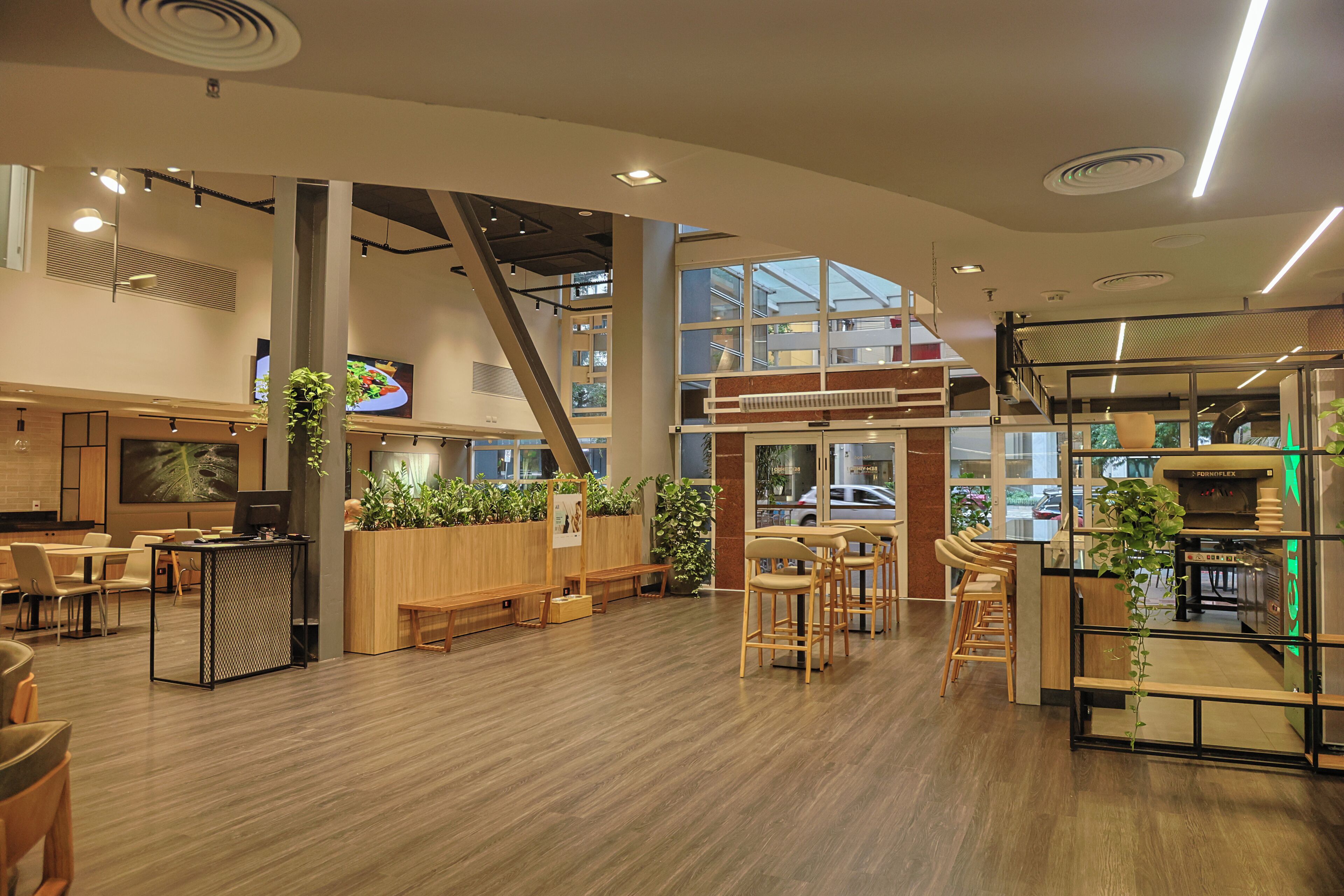 Un interior moderno con suelo de madera, zonas de estar y una cocina con cafetera.
