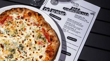 Una pizza sobre un plato blanco, con un menú a un lado.