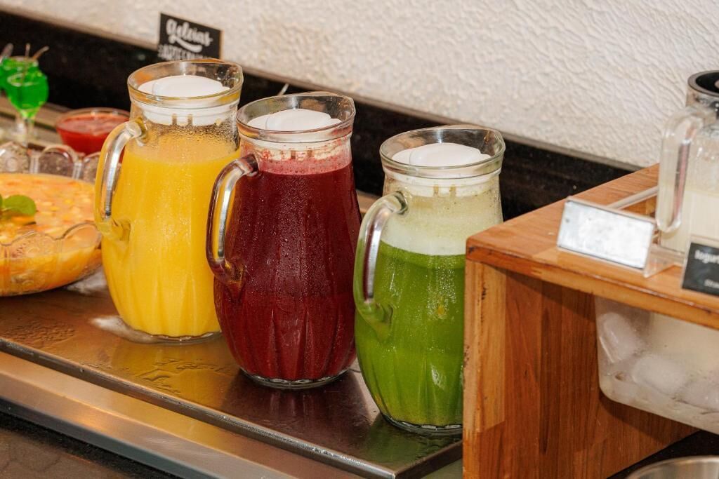 A beverage station with three pitchers of different colored drinks.