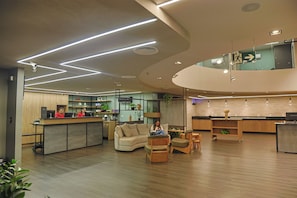 A modern interior with a reception desk, seating area, and a kitchen.