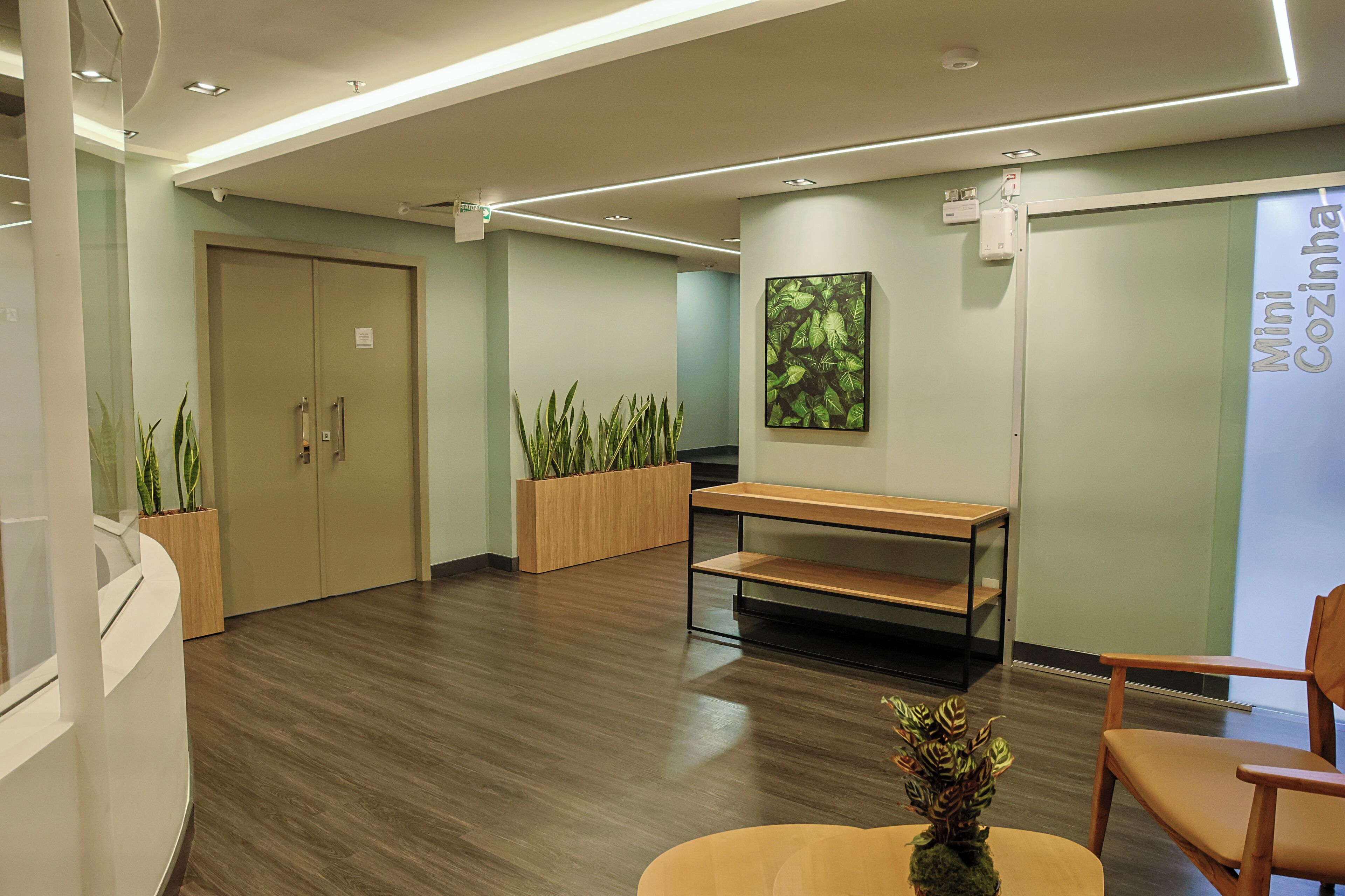 A reception area with a wooden bench, a plant, and a wall-mounted sign.
