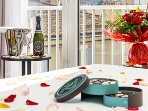 A table with a bottle of wine, glasses, a bouquet of red roses, and a box of chocolates on a balcony with a view. - ibis Millau (Millau)