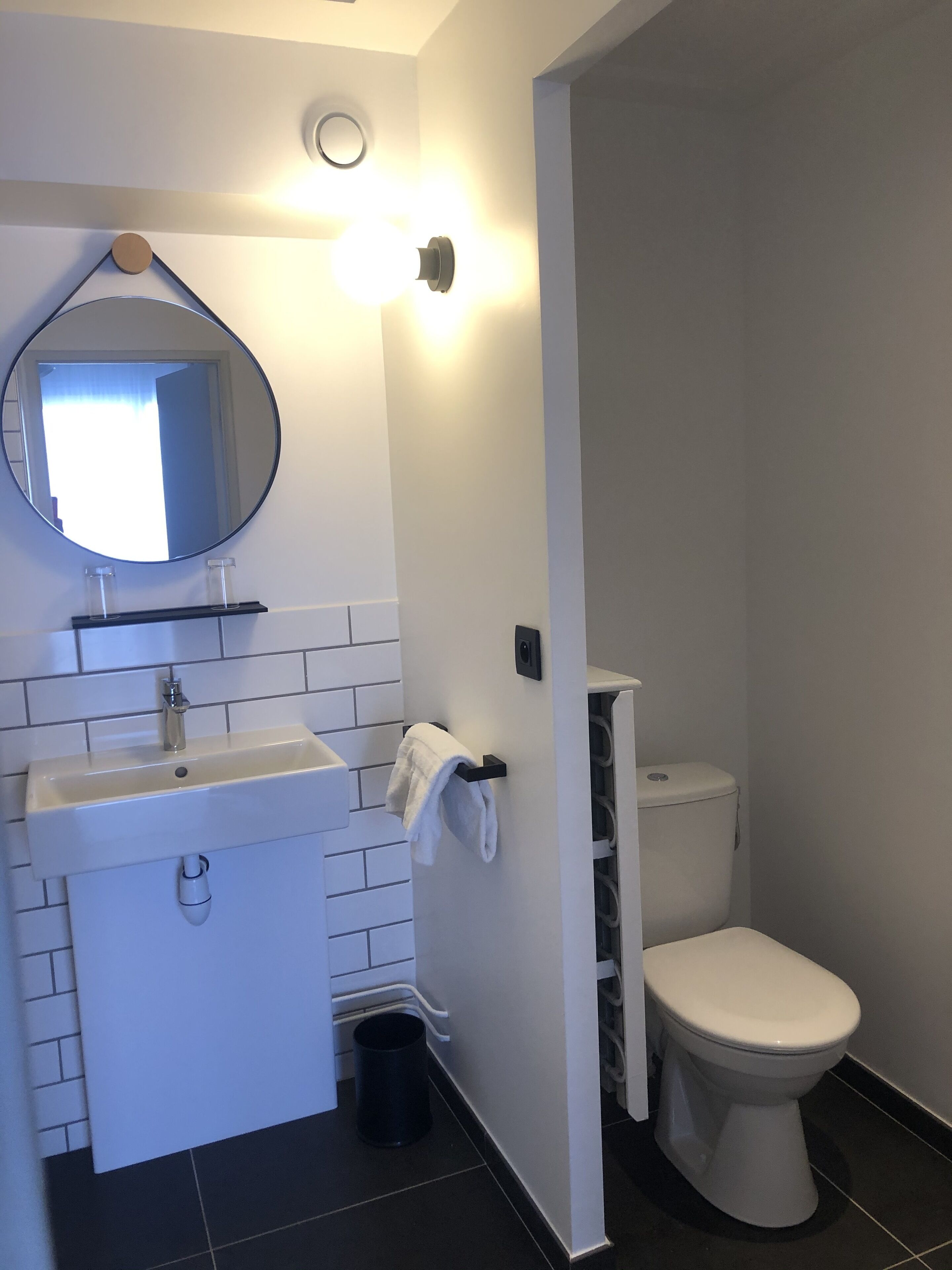 Une salle de bain moderne avec un lavabo blanc, un miroir et des toilettes.