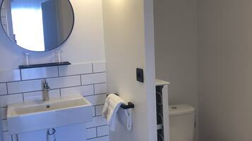 Une salle de bain moderne avec un lavabo blanc, un miroir et des toilettes.