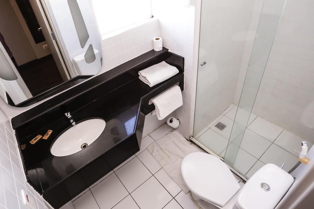 A bathroom with a black sink, white toilet, and a glass shower enclosure.