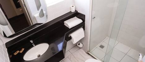 Un baño con lavamanos negro, inodoro blanco y cabina de ducha de vidrio.