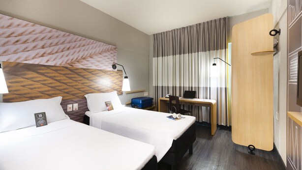 A hotel room with two beds, a desk, a laptop, and a TV. - Ibis Teresina (Teresina)